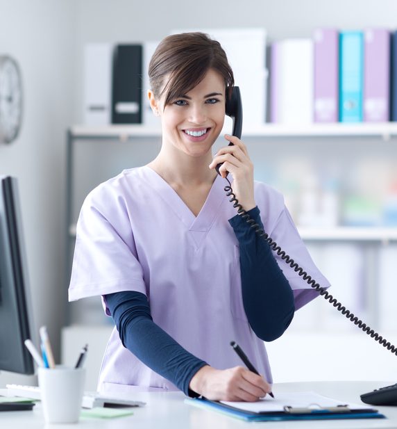 medical reception skills: girl in a scrub suit is answering the phone