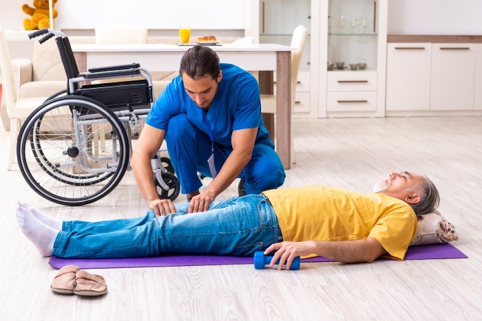 career in disability support: caregiver massaging an elderly man's legs while on the floor