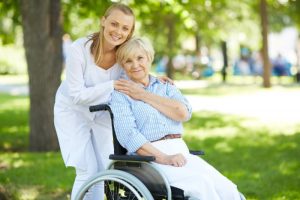 career in disability support: lady stands next to an elderly woman in a wheelchair
