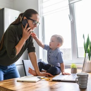 work from home: mum is on the phone with her toddler on the table