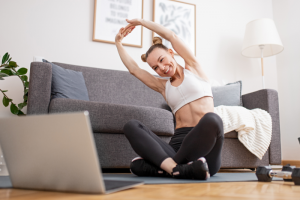 woman is exercising on the floor while facing her laptop