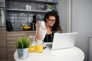 work-from-home: woman is holding a mug while working on her laptop