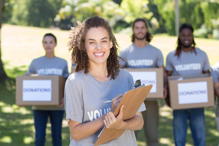 career in community services: woman holding some folders and envelopes with volunteers in the background