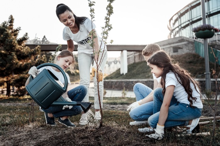 career in community services: woman teaching kids how to plant and water trees