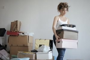 decluttering: a girl is carrying storage boxes with a background of more storage boxes